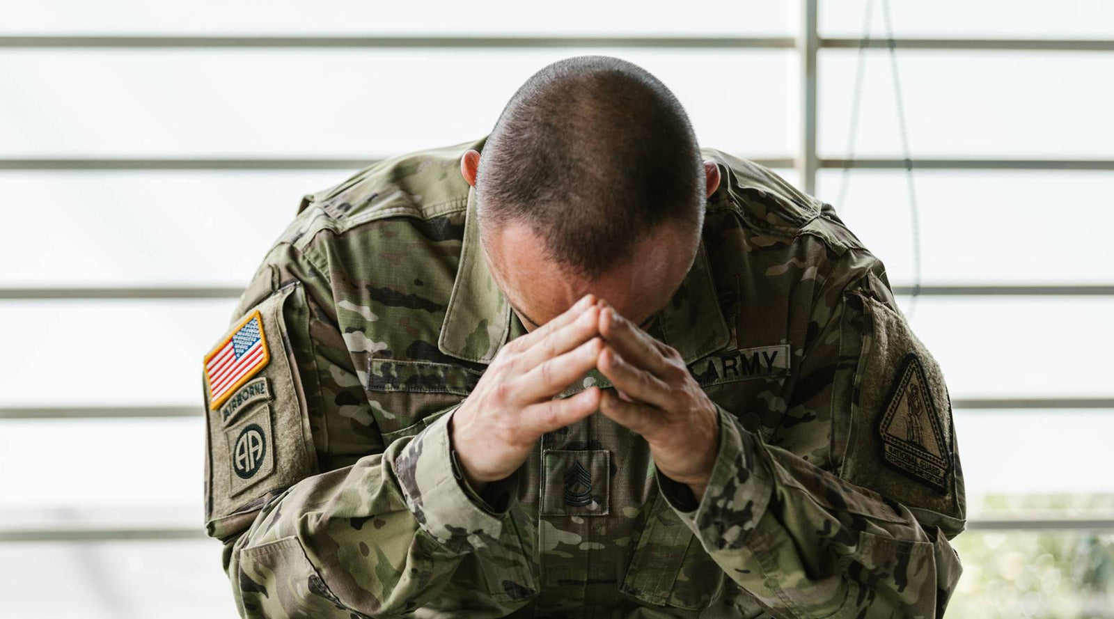 US Army person hands on head looking tired.