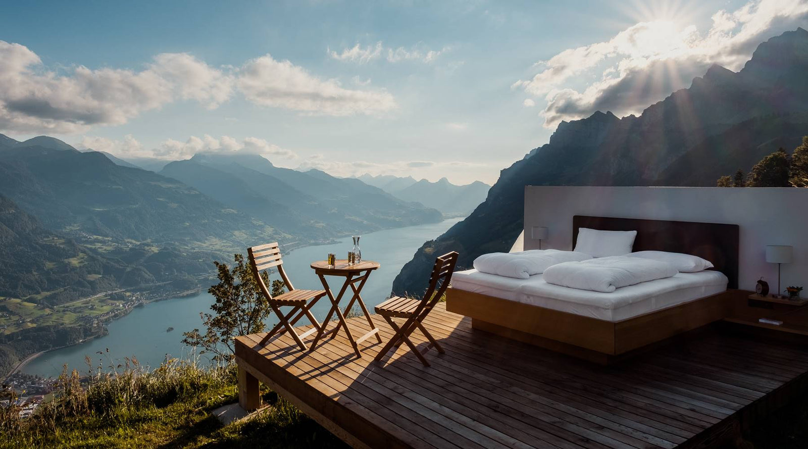 Bedroom setup outdoors in the mountains above a lake with the sun rising.