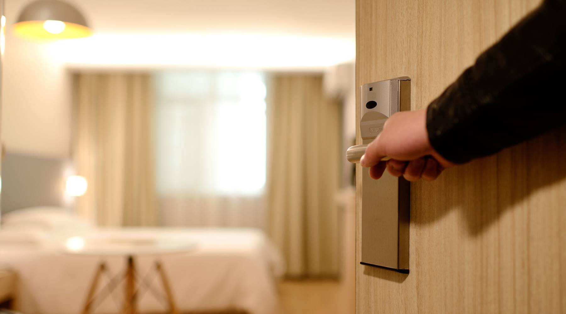 Hand opening door to show hotel bed.