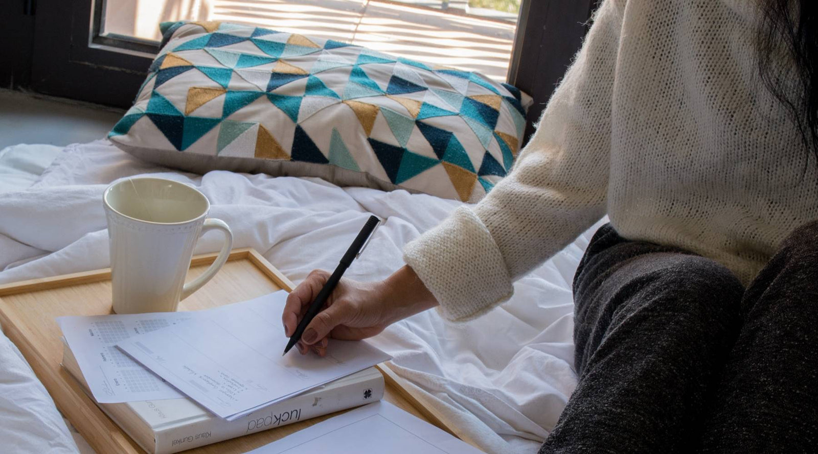 Women taking notes in bed with a cup of coffee.
