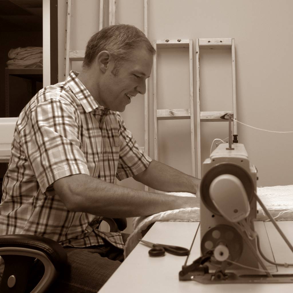 Man sewing a mattress cover.
