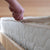 Organic cotton mattress cover being unzipped by a hand.