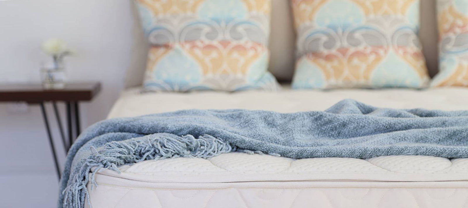 Spindle latex mattress in bedroom with pillows and nightstand.